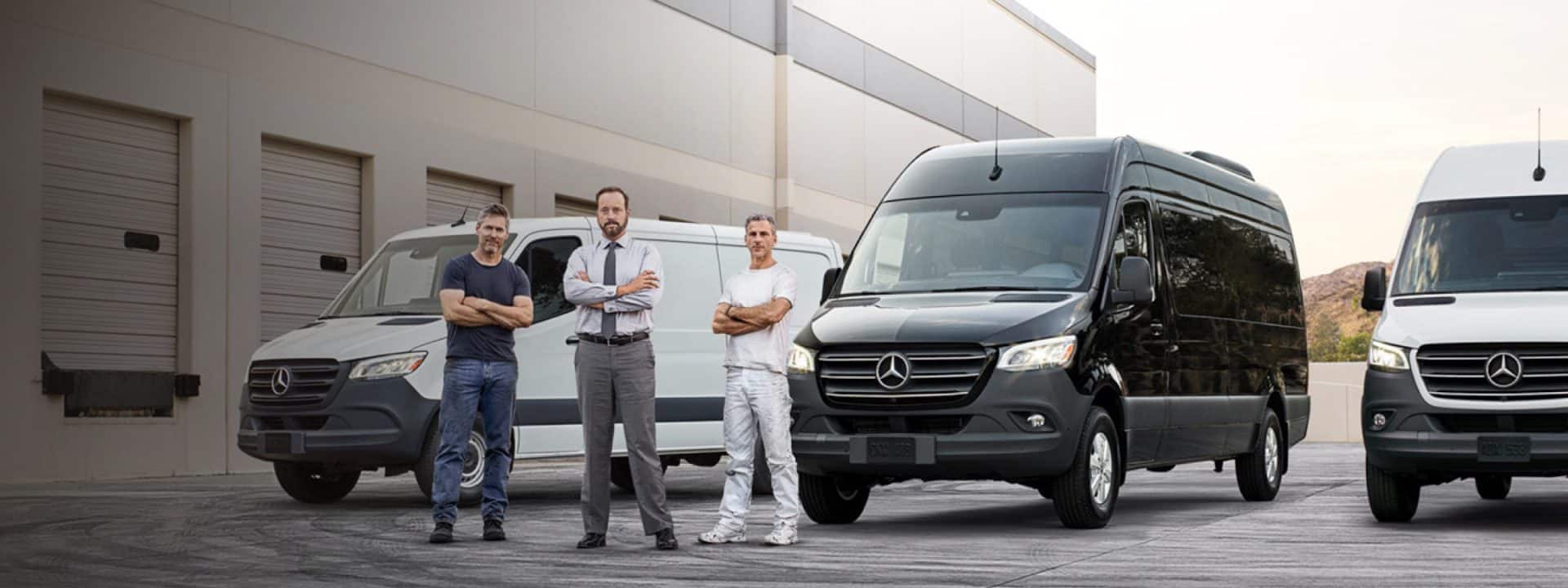Three people standing in front of different Mercedes-Benz vans