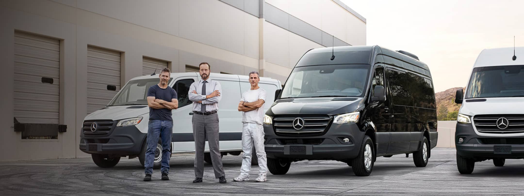 Three people standing in front of different Mercedes-Benz vans