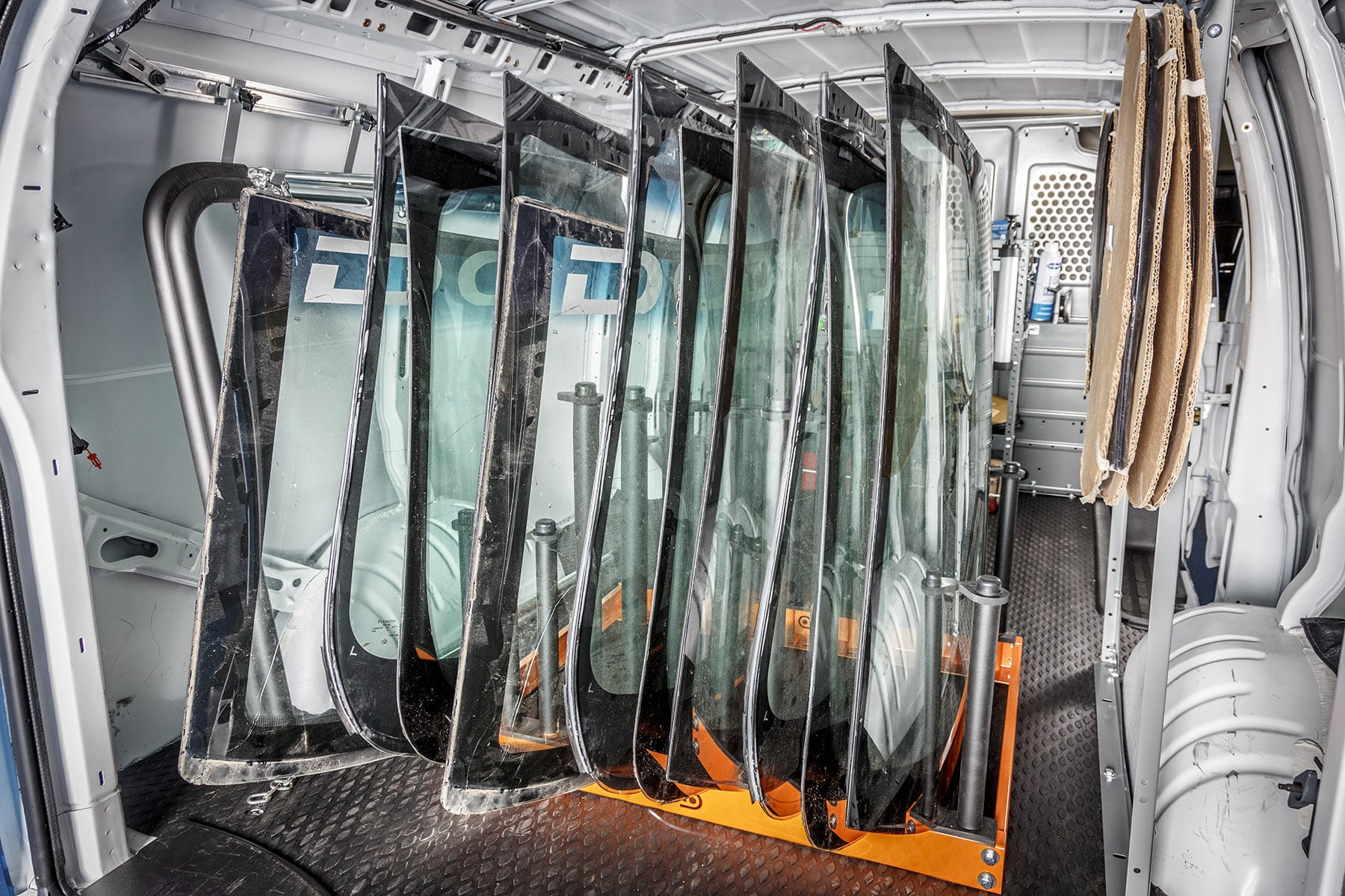 Interior commercial van upfit for auto glass repair technicians with organized storage racks, shelving, and secure glass transport systems