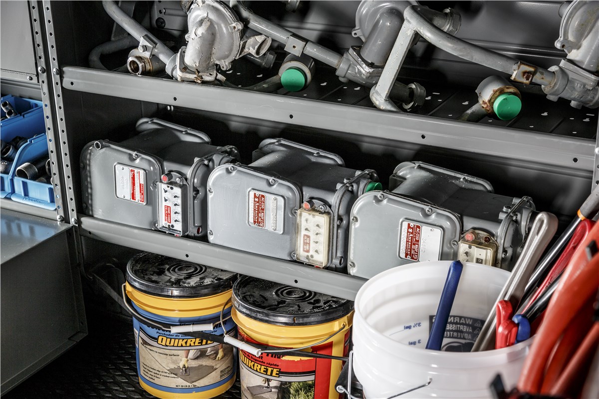 Interior of a commercial cargo van featuring organized metal shelving and storage bins for tools and parts